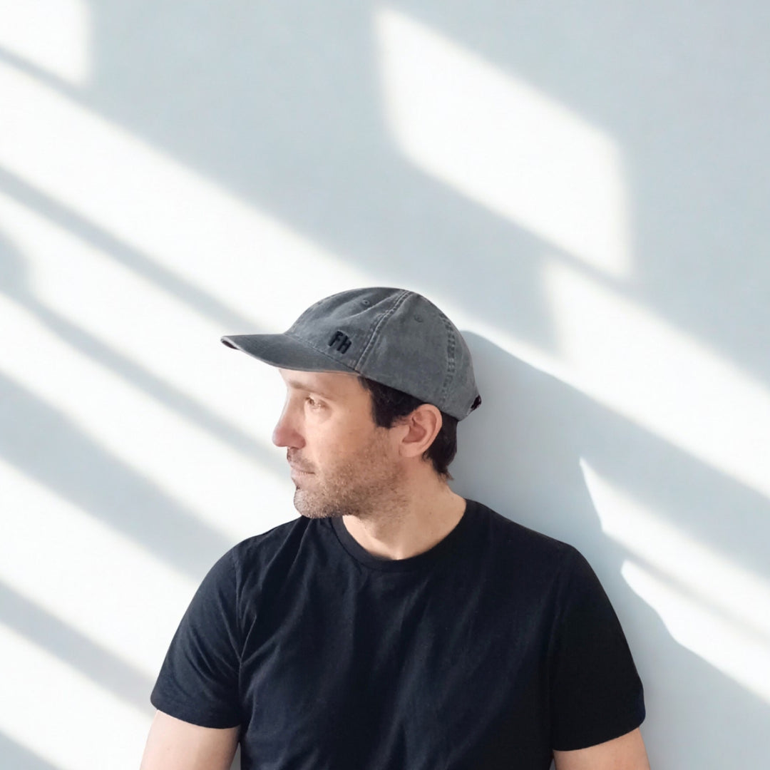 Homme portant une casquette Dad Hat XL gris foncé, vue de profil avec des ombres créées par la lumière.